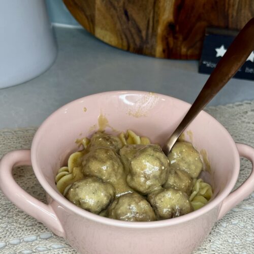 a bowl on a counter with cooked Swedish meatballs and noodles