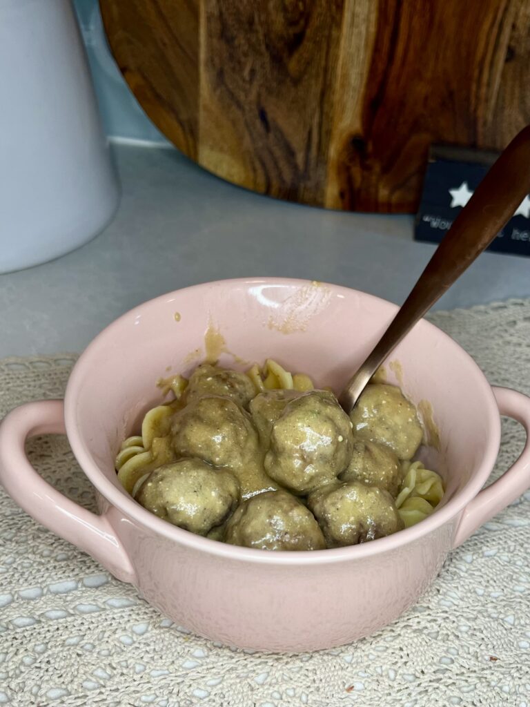 a bowl on a counter with cooked Swedish meatballs and noodles