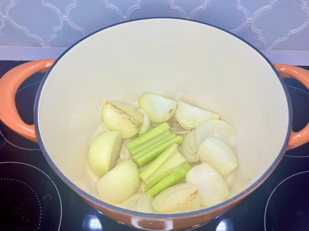 onion and celery being browned in a pot