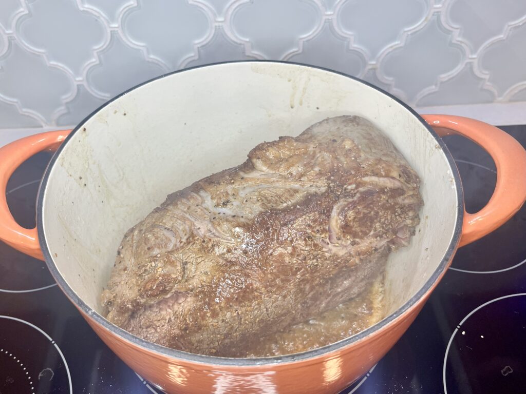 a chuck roast browning in a pot on a stove