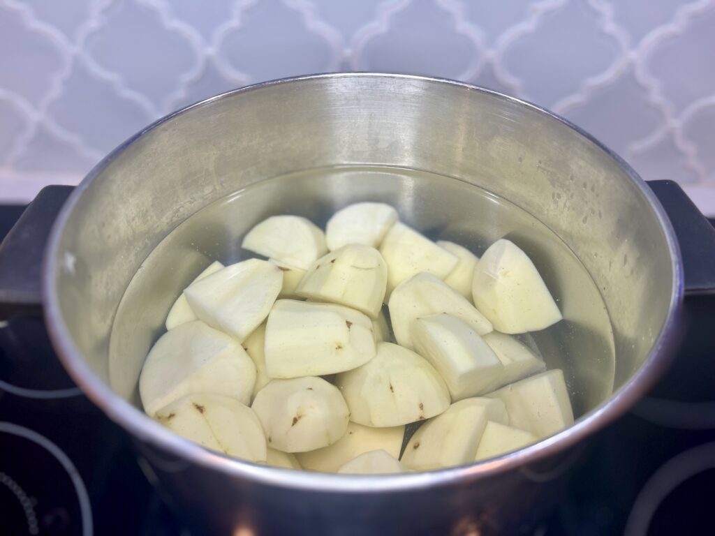 raw potatoes in a pot filled with water on a stove