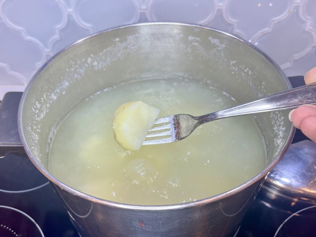 a cooked potato on a fork over a pot