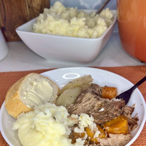 a plate with pot roast, mashed potatoes and buttered bread with a bowl of cooked mashed potatoes