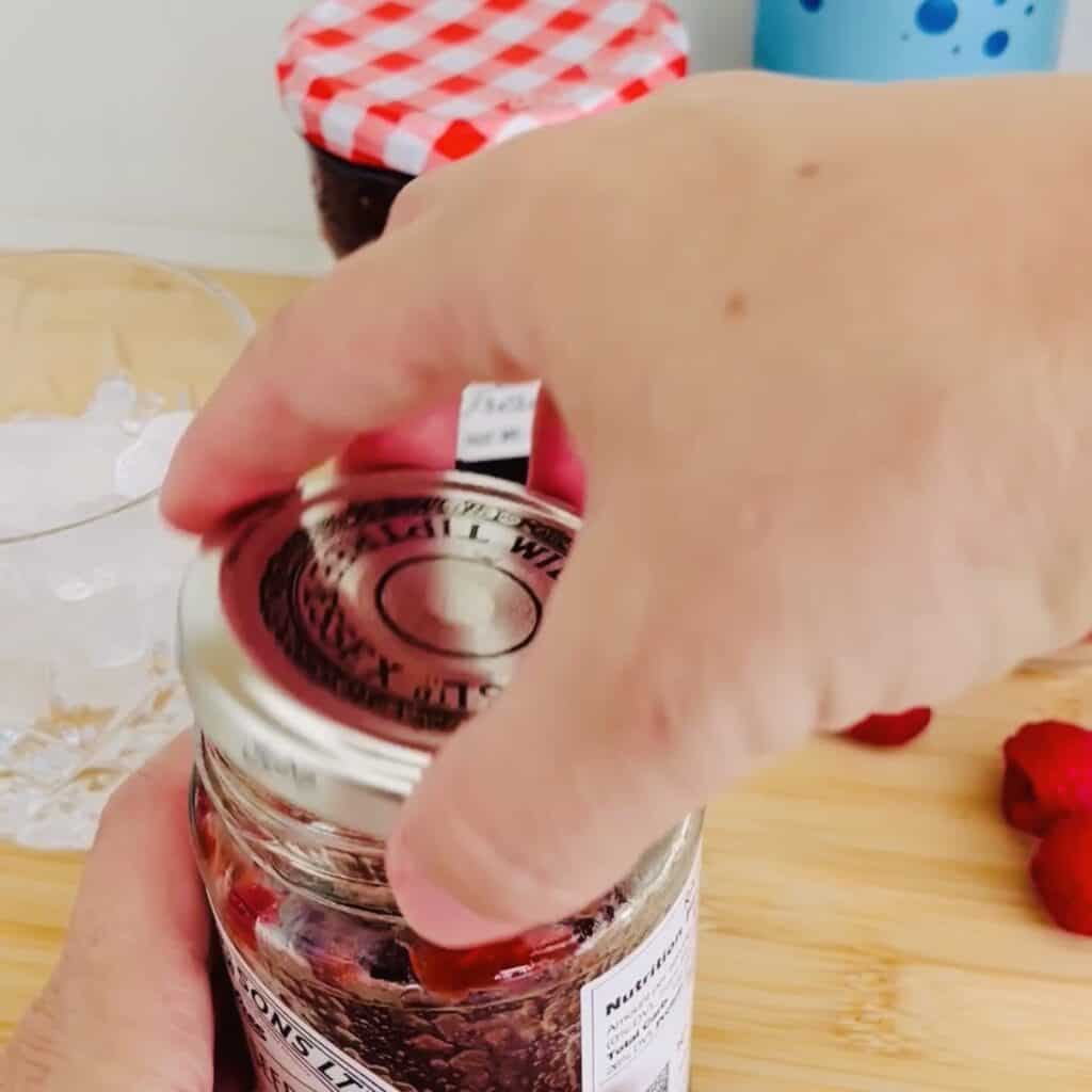 Put in the lid on the jam jar and about to shake it on the brown countertop.