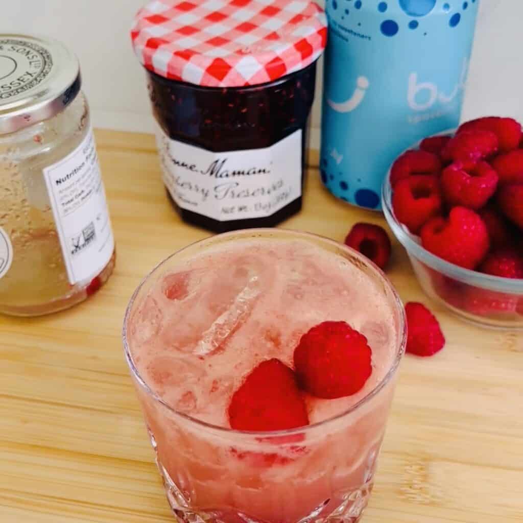  just jamming jam cocktail in a clear glass with garnished with fresh raspberries
