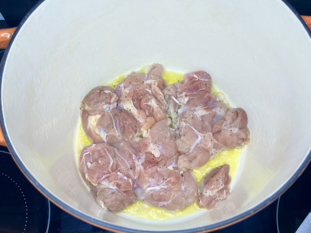 chicken thighs being browned in a pot