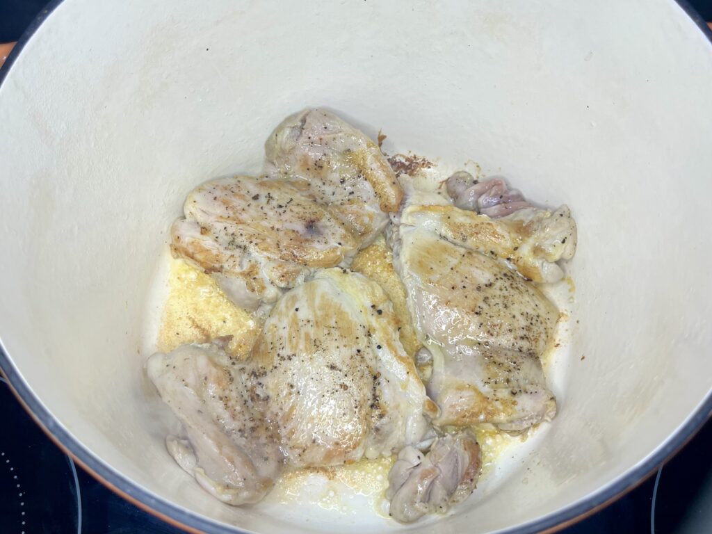 chicken thighs being browned in a pot