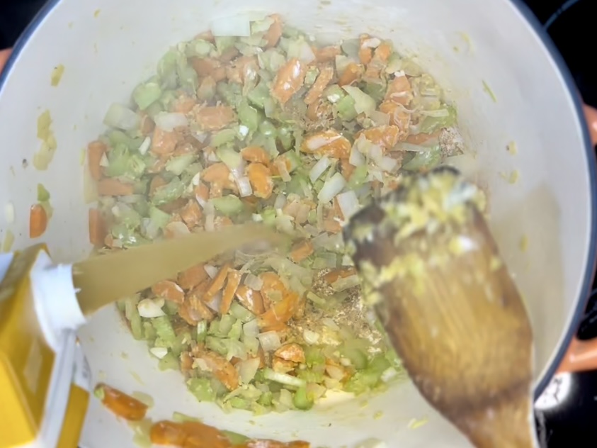 broth being poured into a pot with vegetables