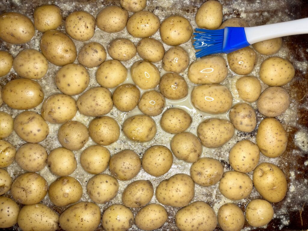 butter being brushed over potatoes