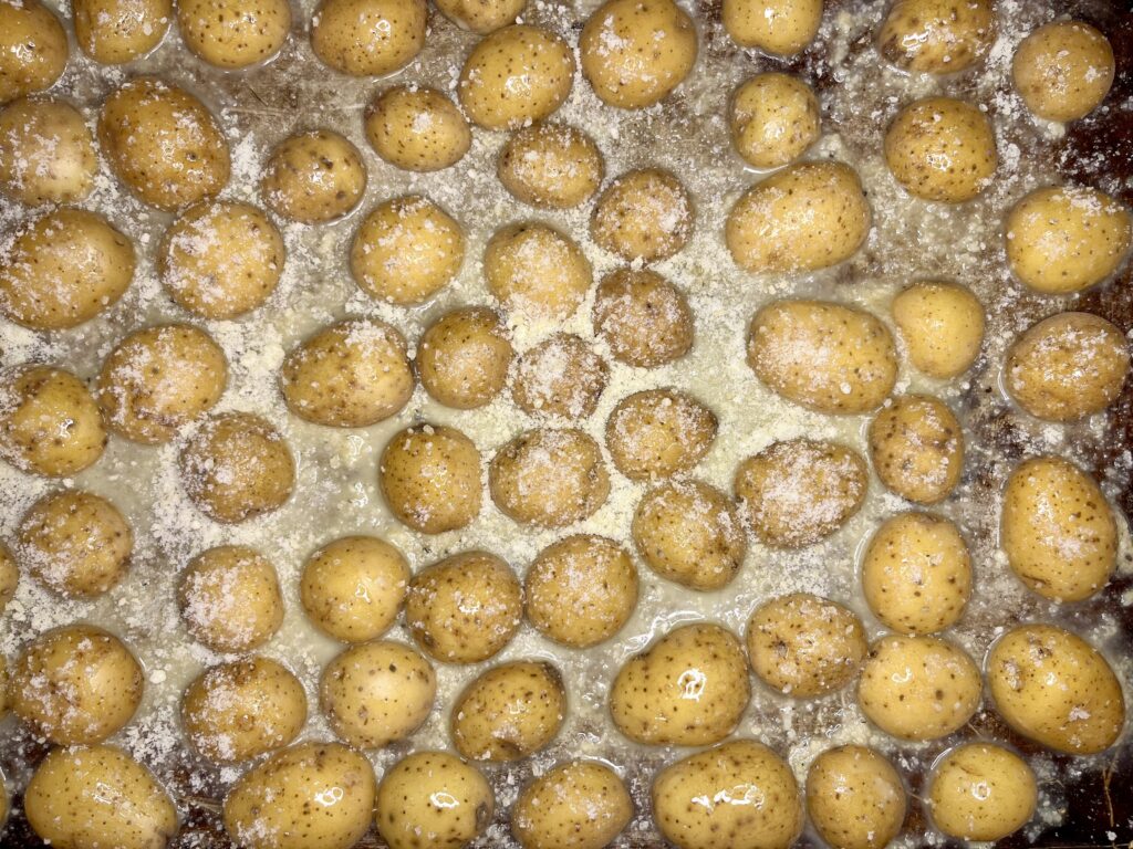 baby potatoes on a baking sheet with seasoning, melted butter, and parmesan