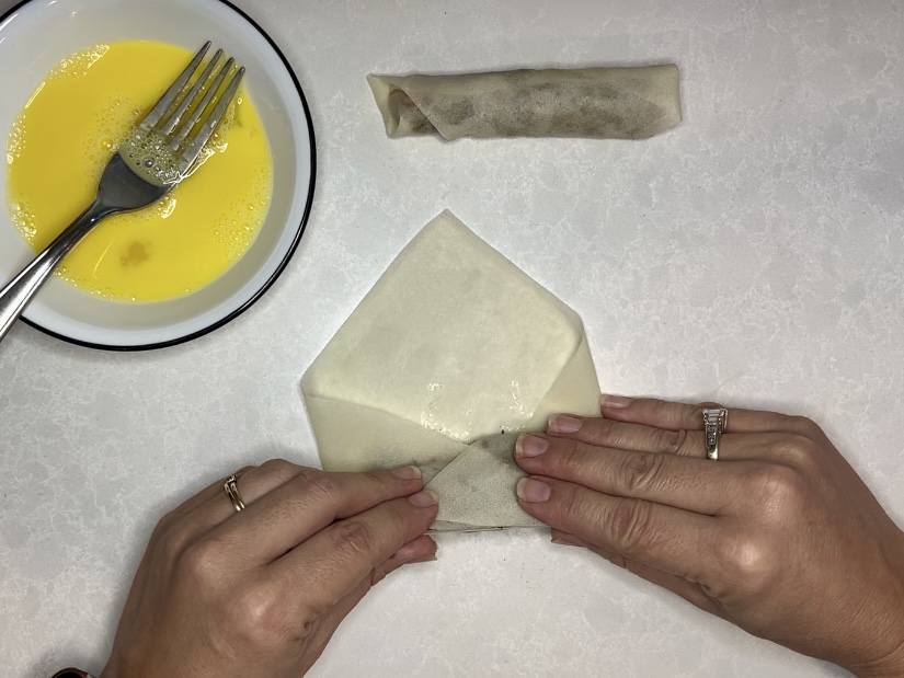 lumpia being rolled up by two hands