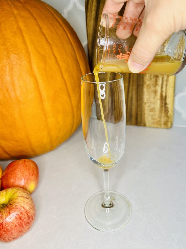 apple cider being poured in to a champagne glass