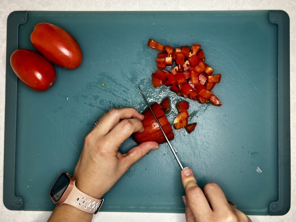 a knife dicing a plum tomato