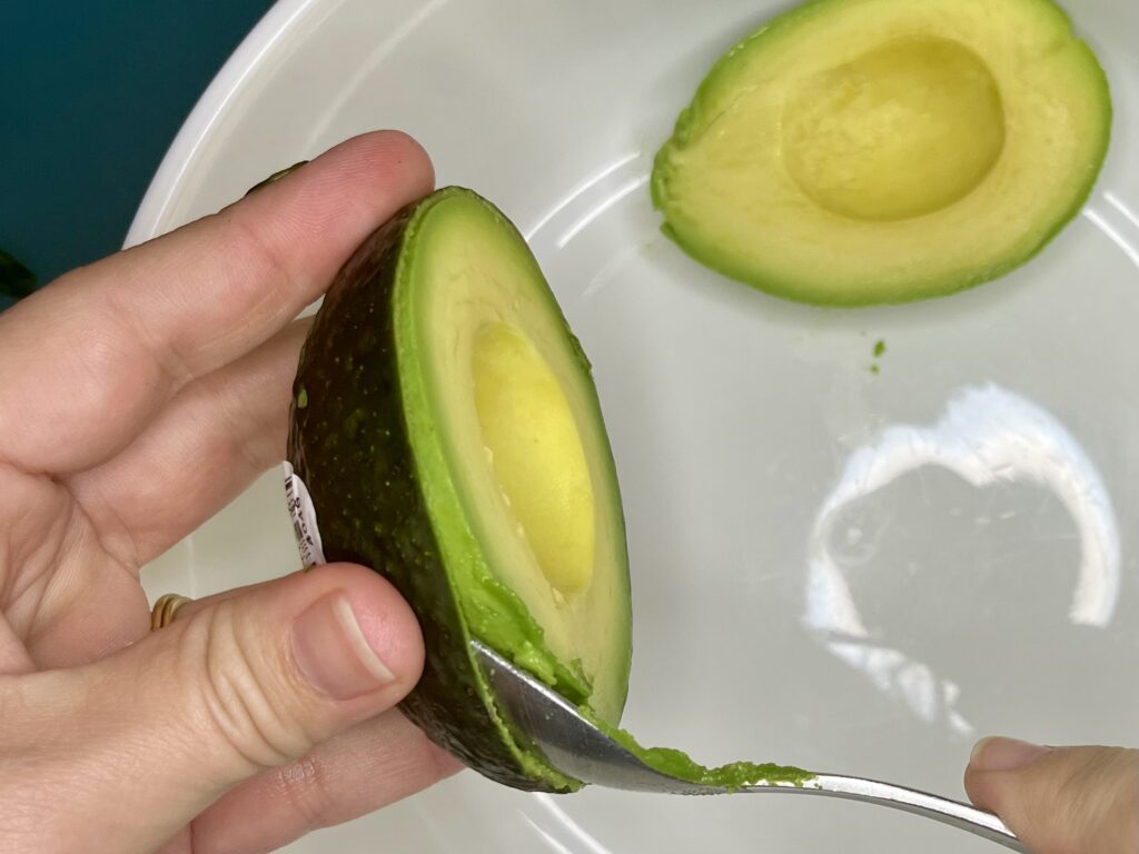 avocado being scooped into a bowl