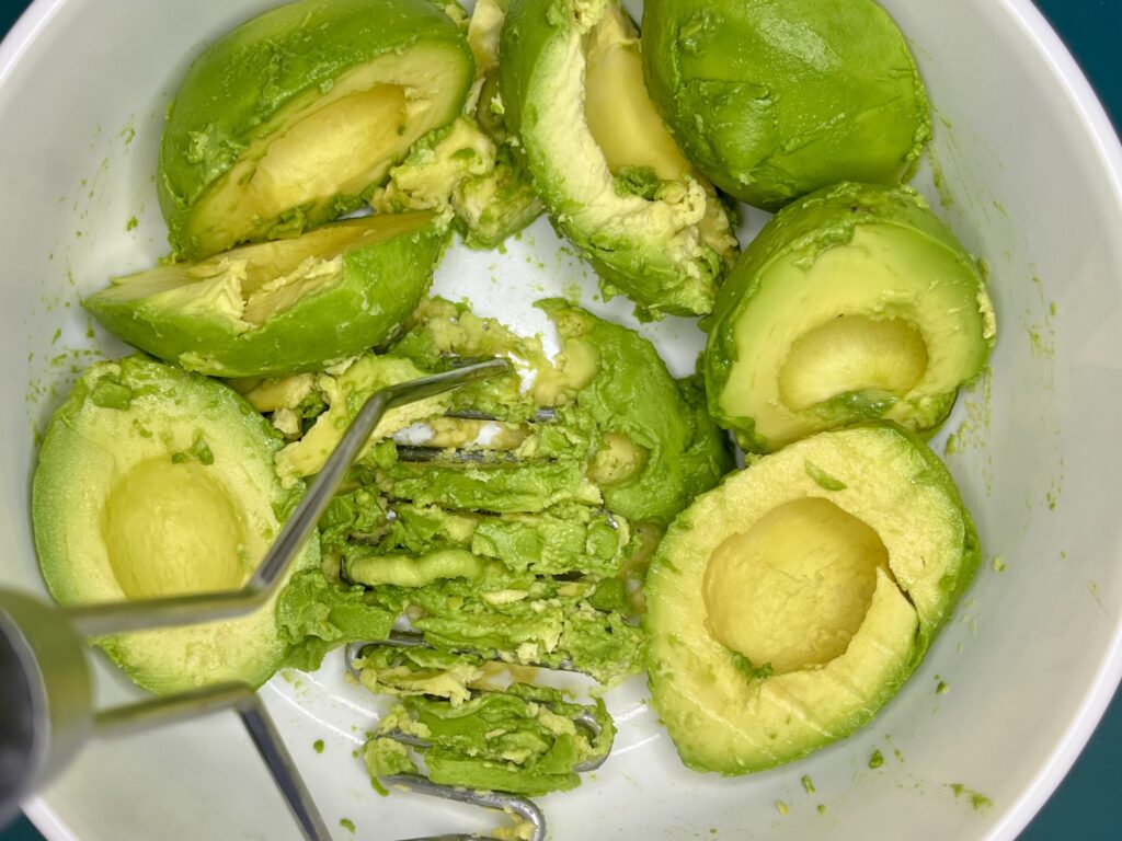 avocados being mashed in a bowl