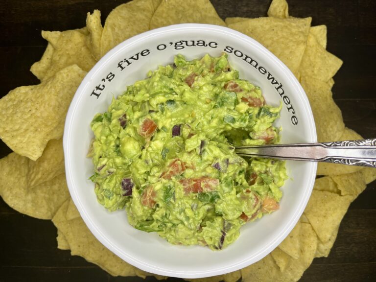 a bowl with guacamole on a counter with tortilla chips