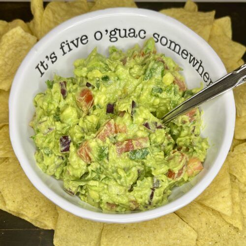 a bowl with guacamole on a counter with tortilla chips