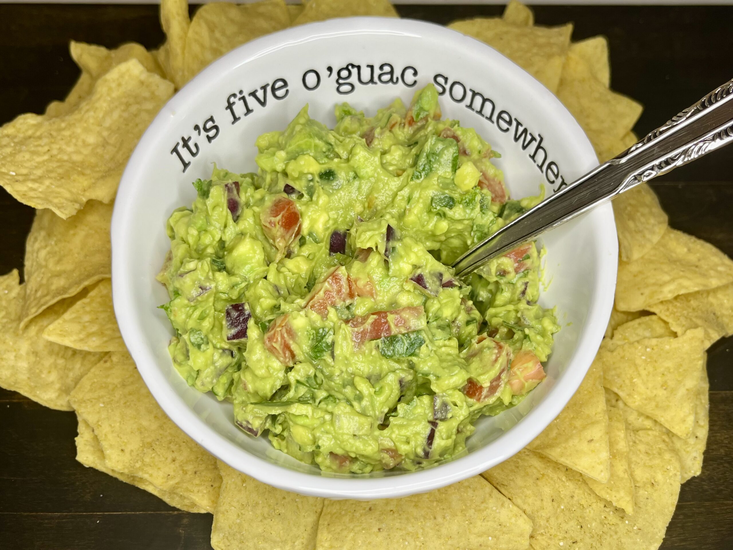 a bowl with guacamole on a counter with tortilla chips