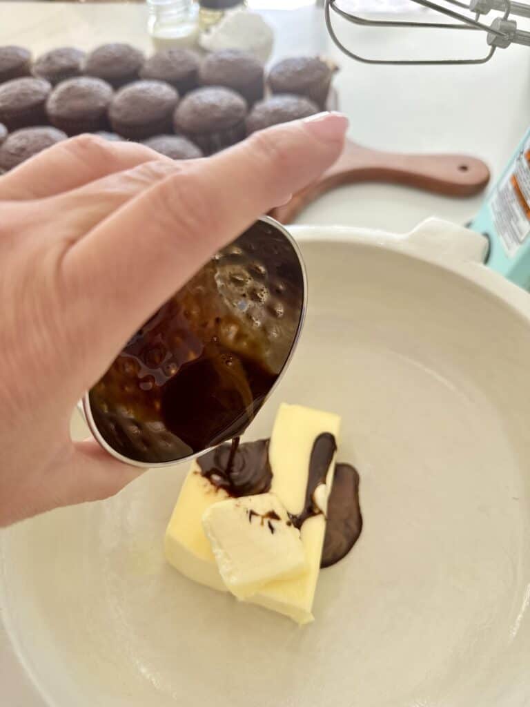 Pouring instant coffee with water over unsalted butter in a off-white colored bowl