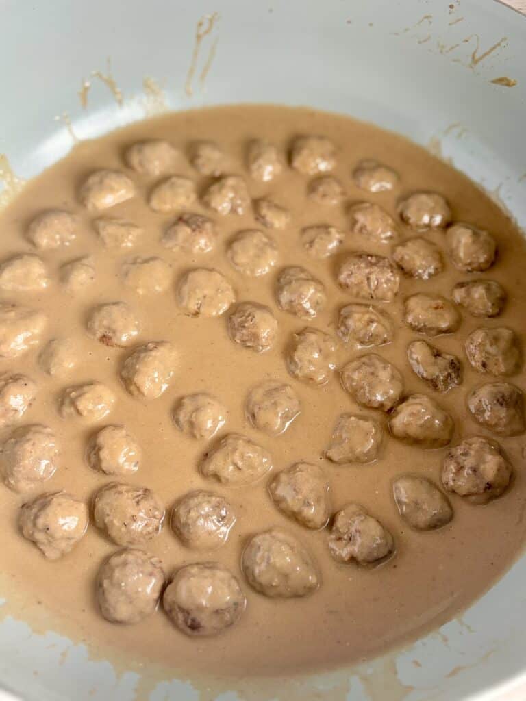 Close-up of Swedish meatballs in a creamy sauce, cooked in a white skillet, ready to serve as part of a traditional Swedish dish.