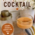 Pumpkin Pie Cocktail in a glass with a creamy orange color, garnished with spices, on a tray with fall-themed decor.