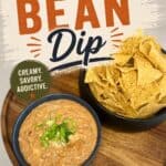 Creamy, savory refried bean dip served with crispy tortilla chips in a black bowl, perfect for snacks or parties, featured on Simply Made Dish website, highlighting delicious Mexican-inspired appetize.