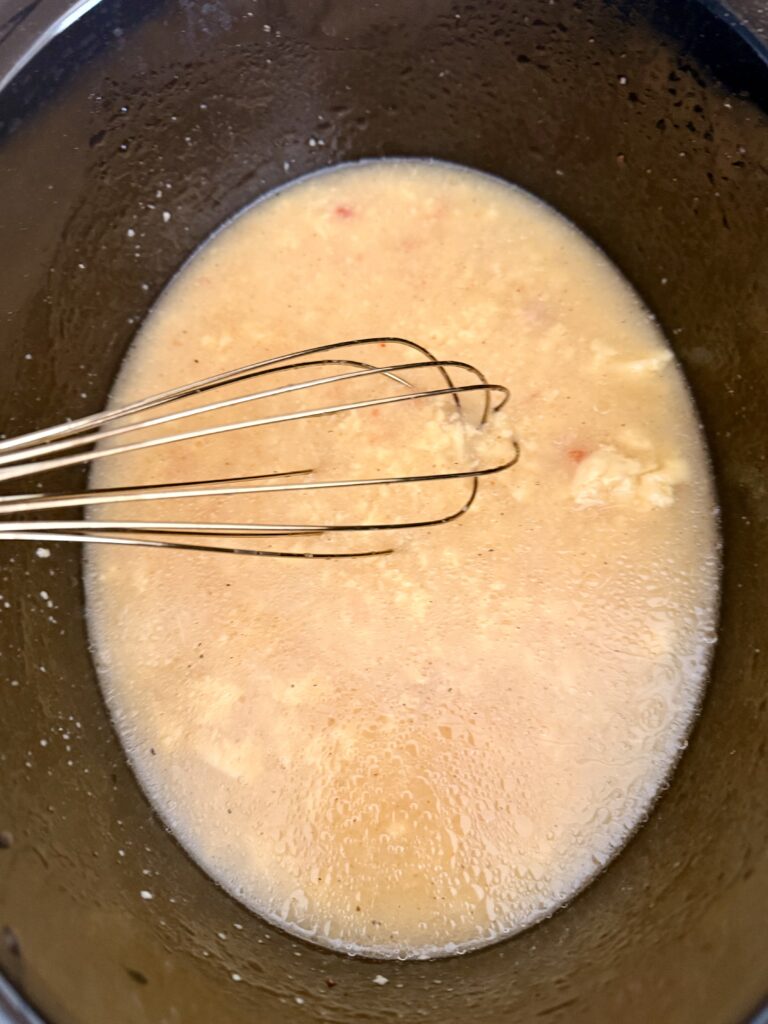 Whisking chicken broth, soup, rice and Italian dressing in a slow cooker on the counter.