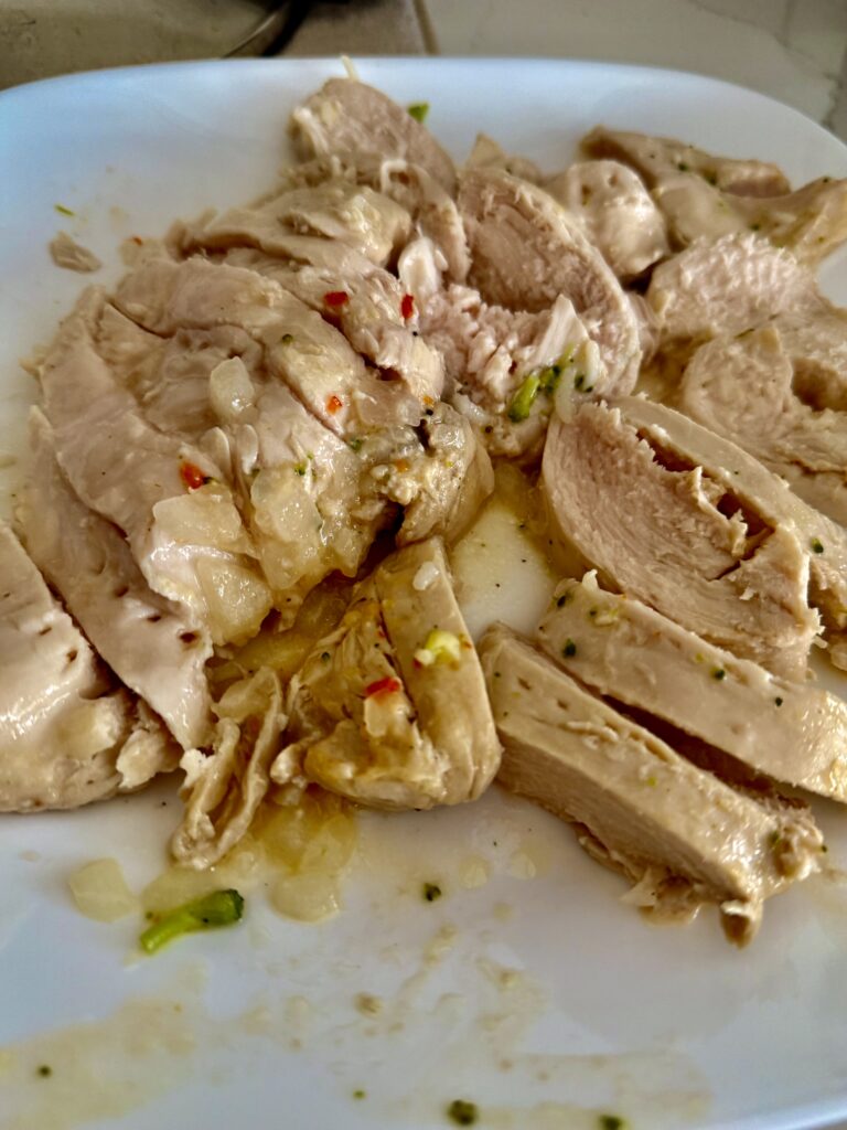 sliced chicken on a white plate on the counter.