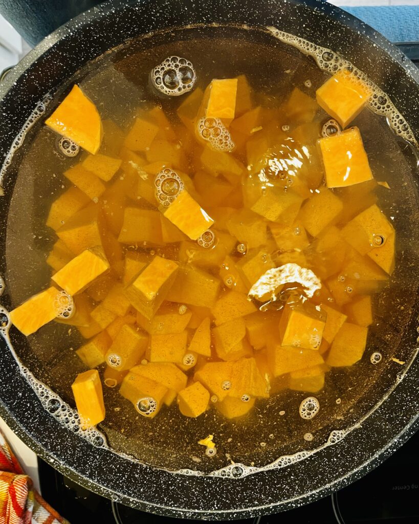 sweet potatoes in boiling water in a black large pot on the stove.