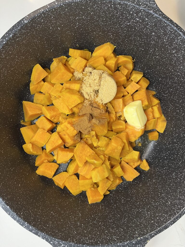 butter, spices and sweet potatoes in a large black pot on the counter