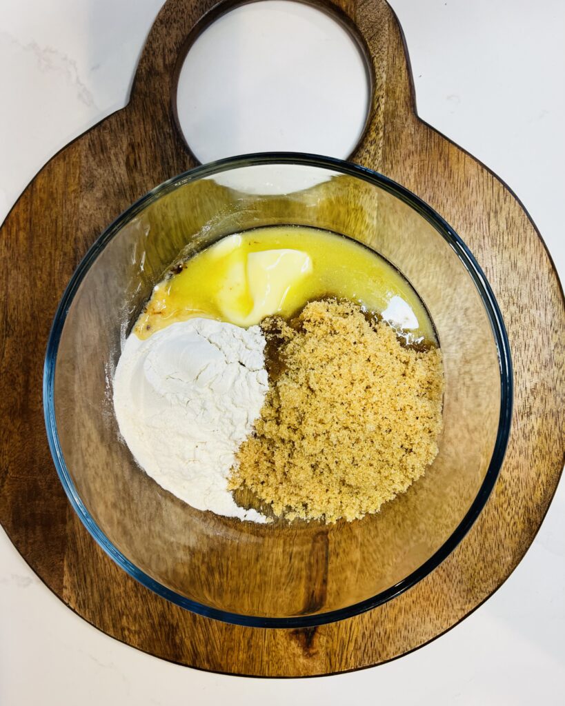 butter, flour, brown sugar in a small glass bowl on a cutting board on the counter.