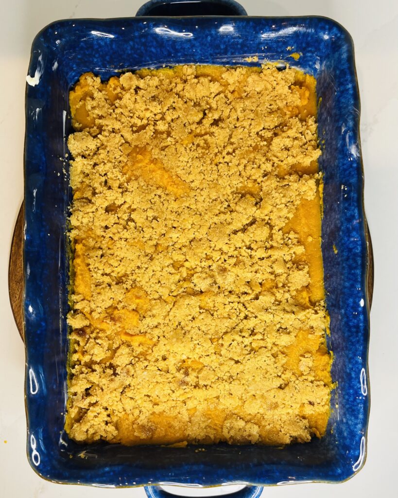 brown sugar topping on top of sweet potatoes in a blue casserole dish on the counter.