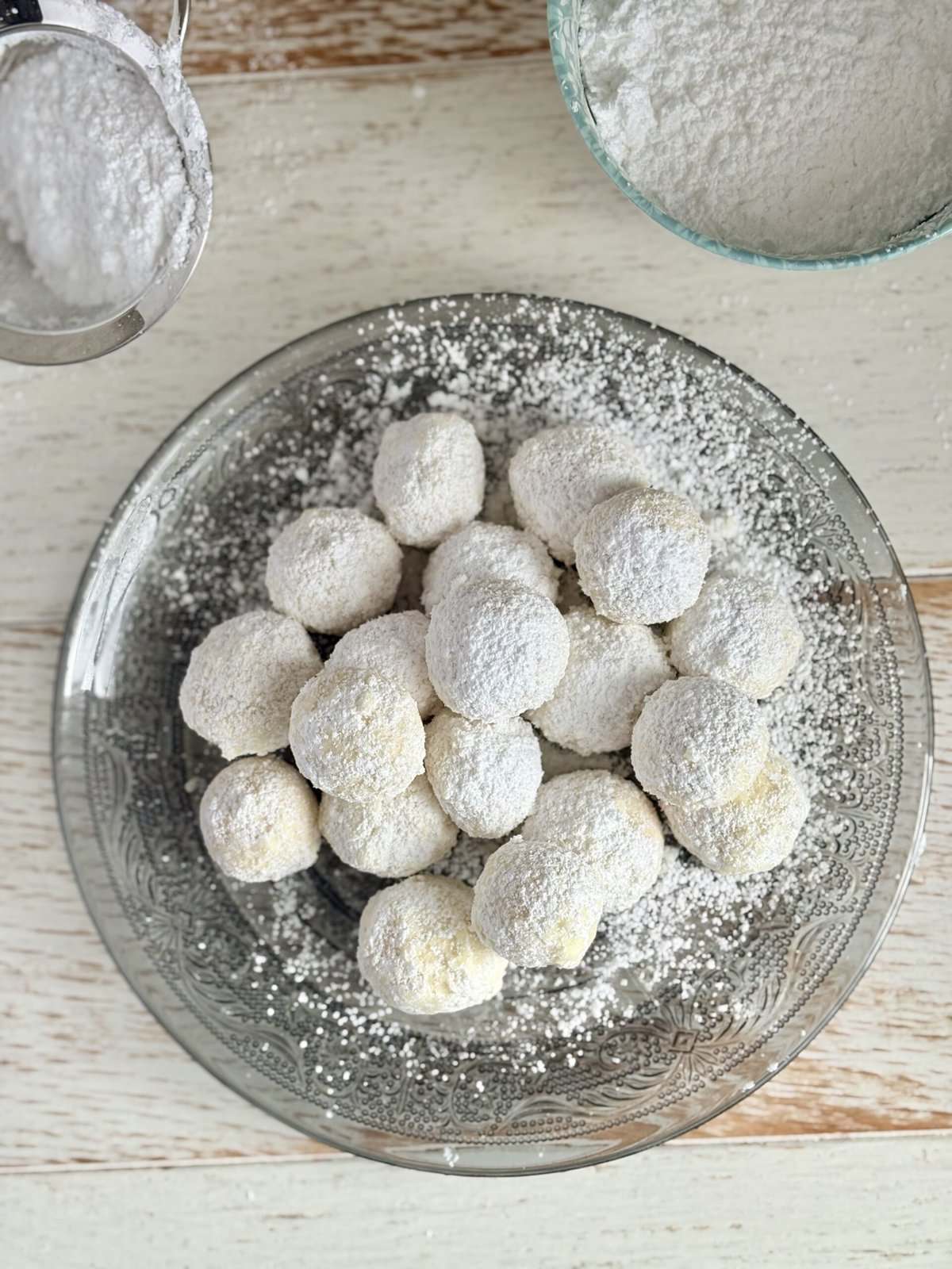 A plate of freshly made Russian Tea Cakes cookies dusted with powdered sugar, ready to serve at holiday parties or as a sweet gift, showcasing a delicious and elegant treat with a melt-in-your-mouth texture.