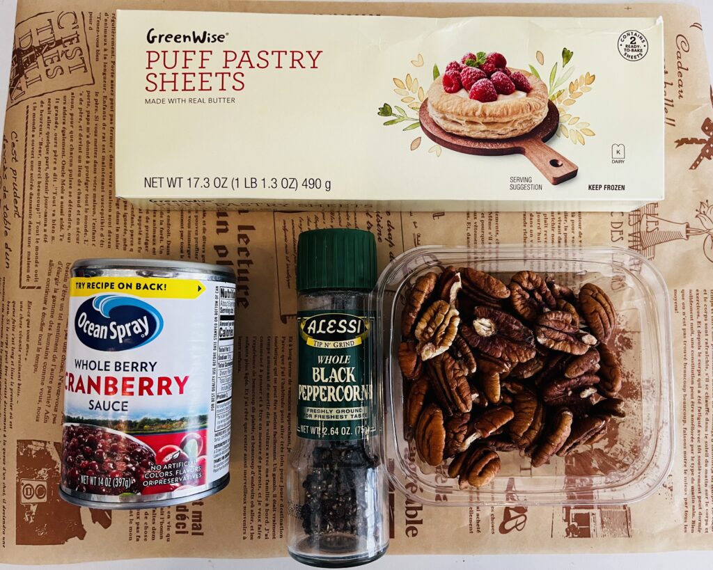 Pecans, black pepper, cranberry sauce and puff pastry sheets on parchment paper on the counter