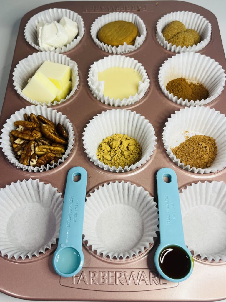 cream cheese, ginger snap cookies, butter, condensed sweetened milk, ground ginger, ground cinnamon, ground nutmeg, whole pecans, vanilla extract, lemon juice and brown sugar in muffin paper cups in a muffin tin on the counter.