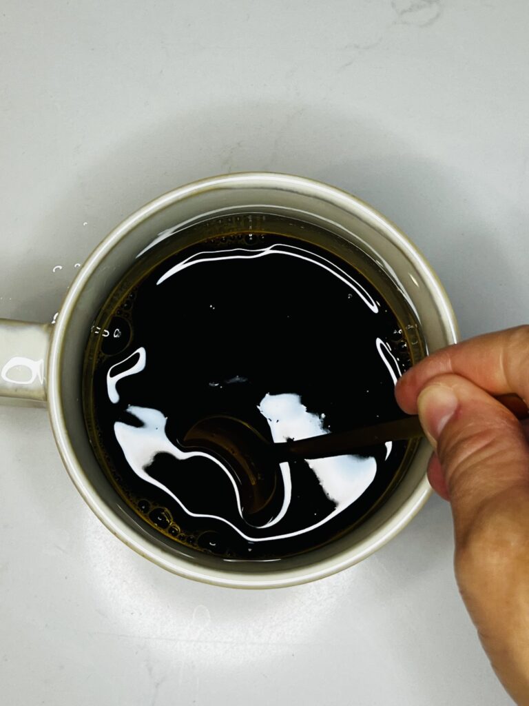 mixing water and instant espresso in a cup on the counter