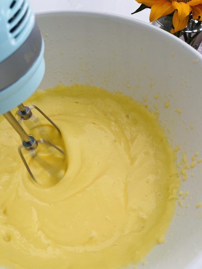 electric mixer mixing vanilla pudding in  large white bowl on the counter