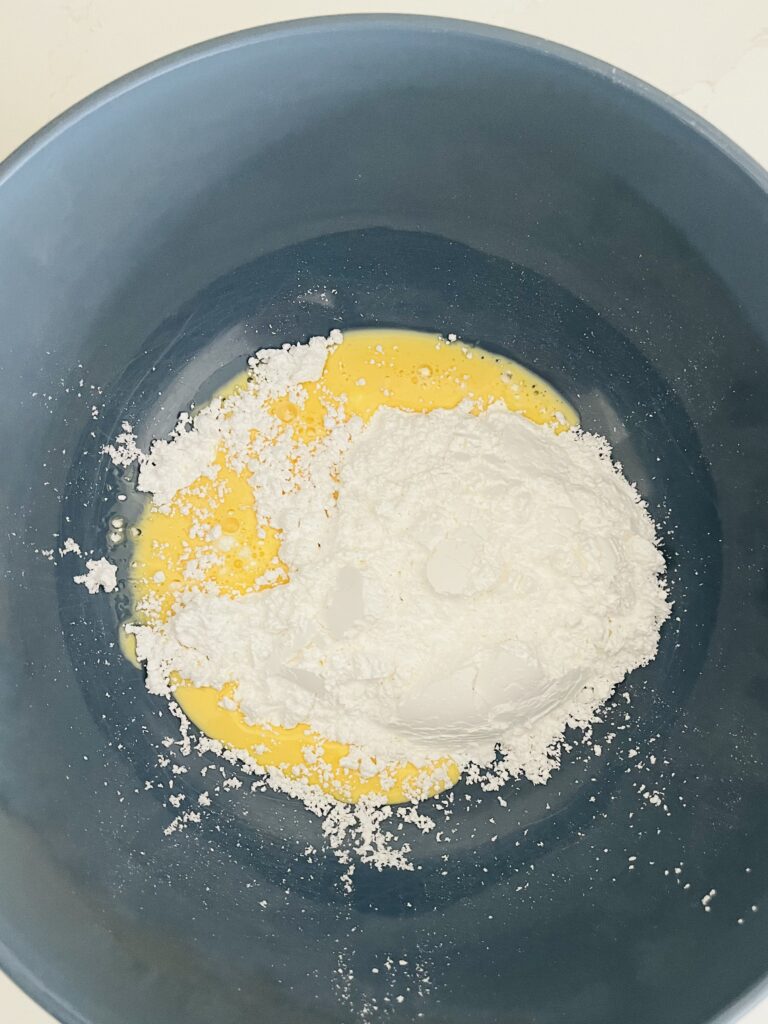 powdered sugar and eggnog in a large blue bowl on the counter