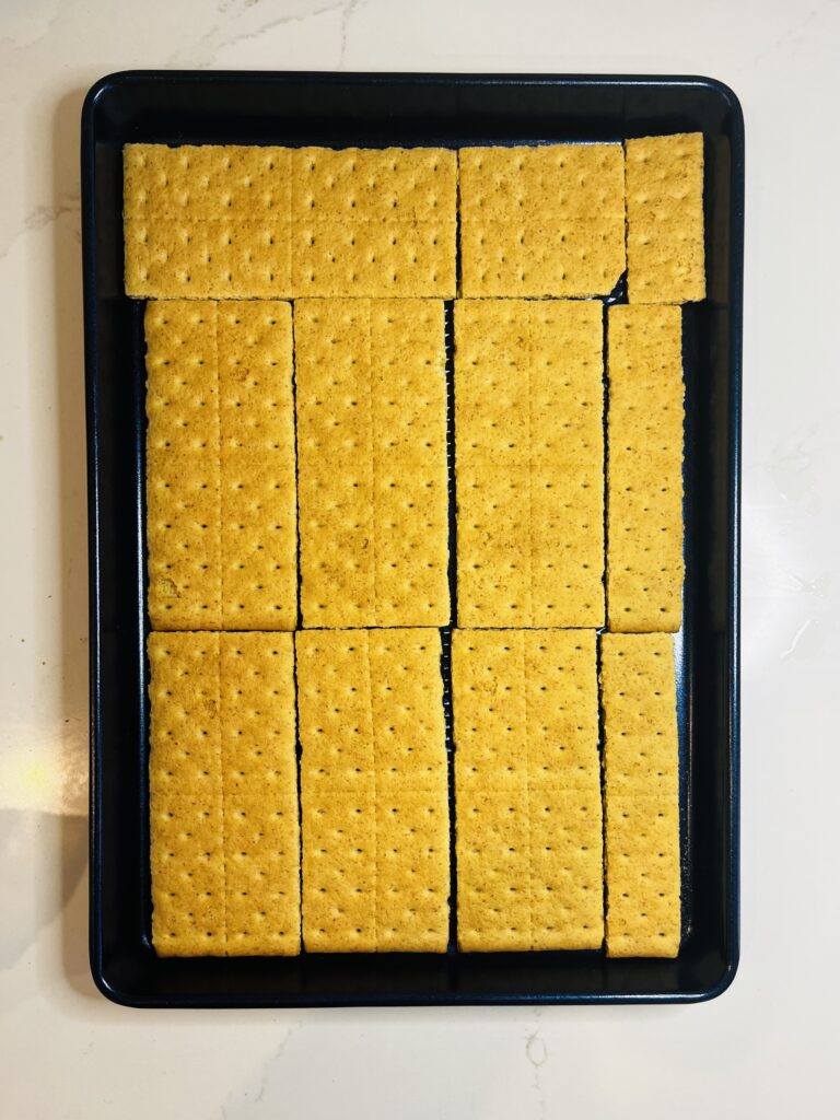 graham crackers lining a blue baking sheet, on the counter