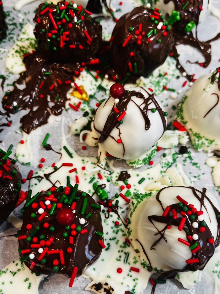 Decorated Festive Oreo Balls on a parchment paper baking sheet on the counter.