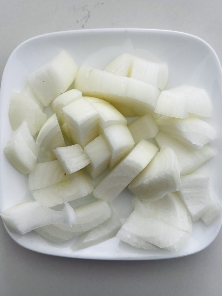 roughly chopped onions on a white plate on the counter.