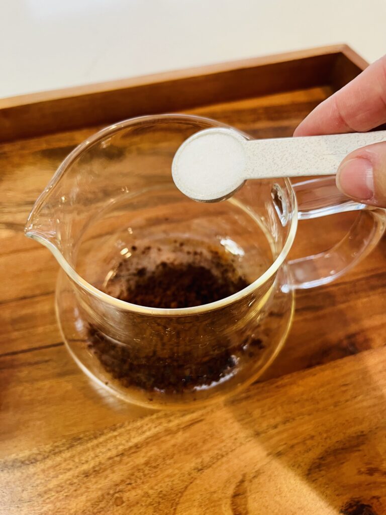 instant coffee in a glass cup. pouring sugar into the cup with instant coffee on a brown tray on the counter.