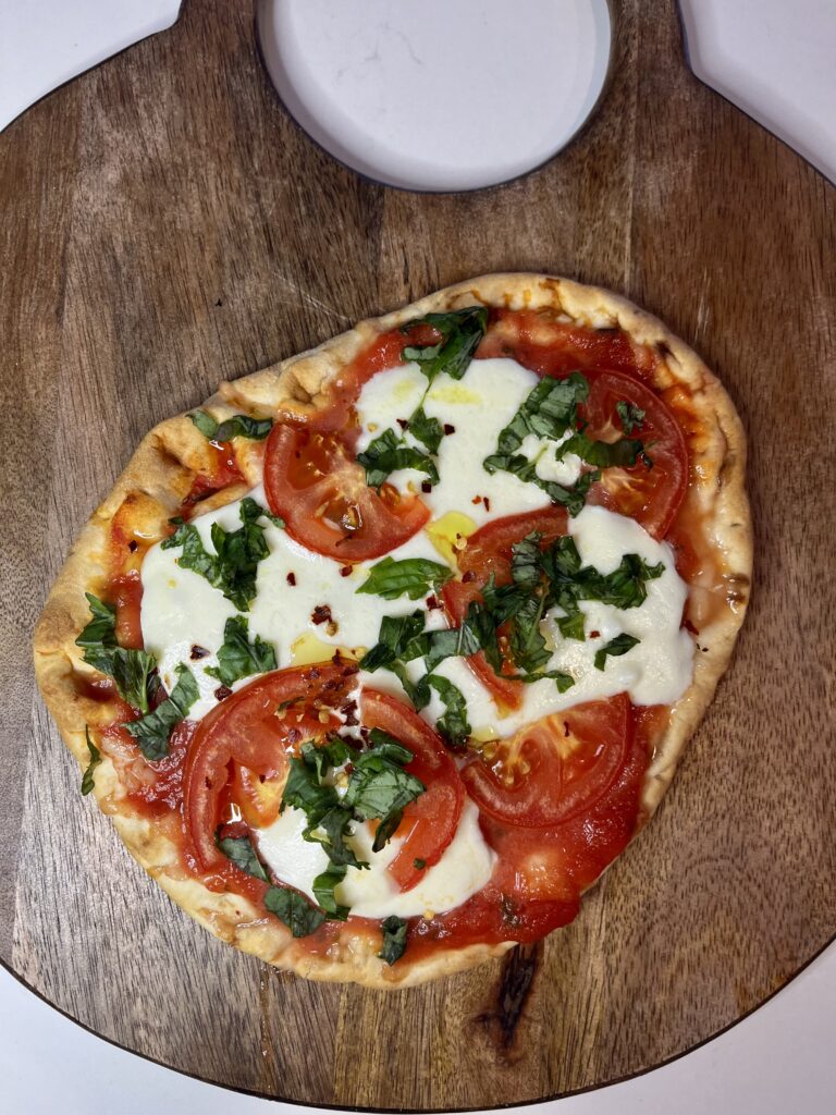 Simple Margherita Pizza on a brown cutting board on the counter.