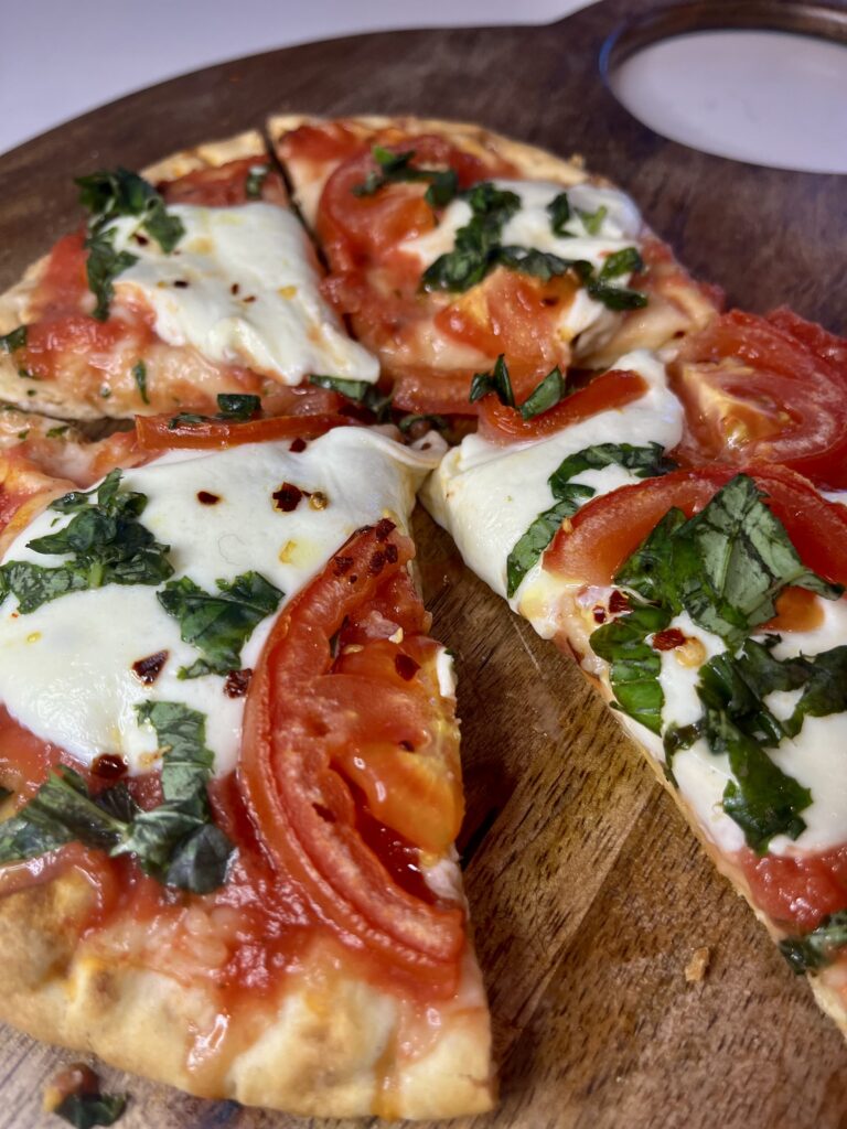 Simple Margherita pizza on a brown cutting board on the counter