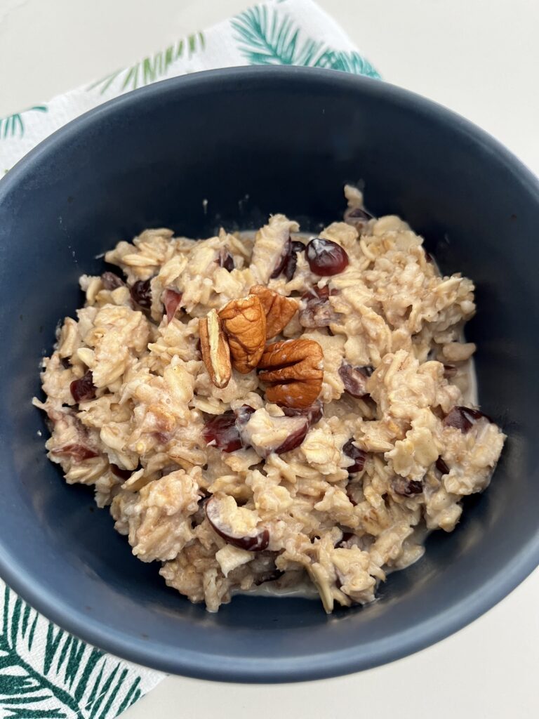 Merry Morning Oatmeal topped with pecans in a blue bowl on the counter.