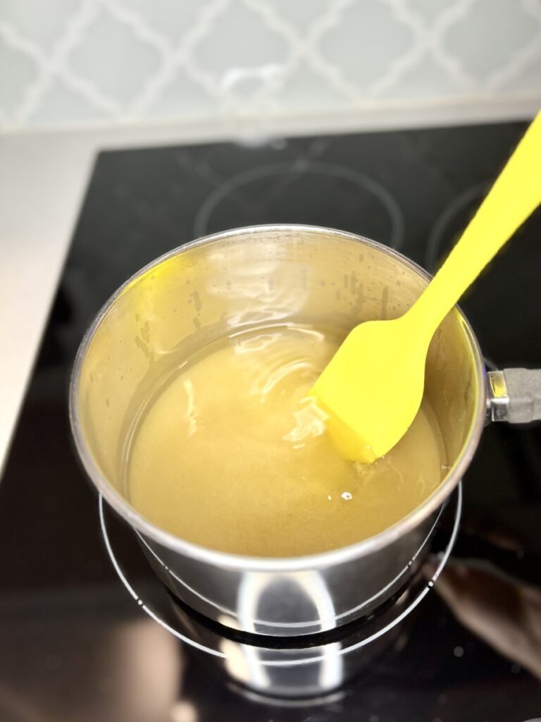 simple syrup ingredients in a saucepan on a stove being stirred