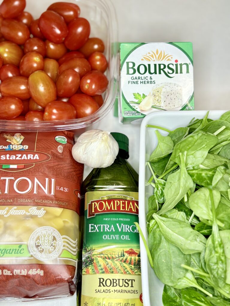 grape tomates, Boursin cheese spread, baby spinach, garlic, olive oil and rigatoni pasta on a counter