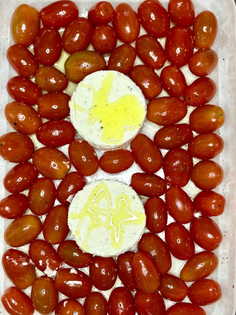 Boursin cheese in a baking dish with olive oil and tomatoes 