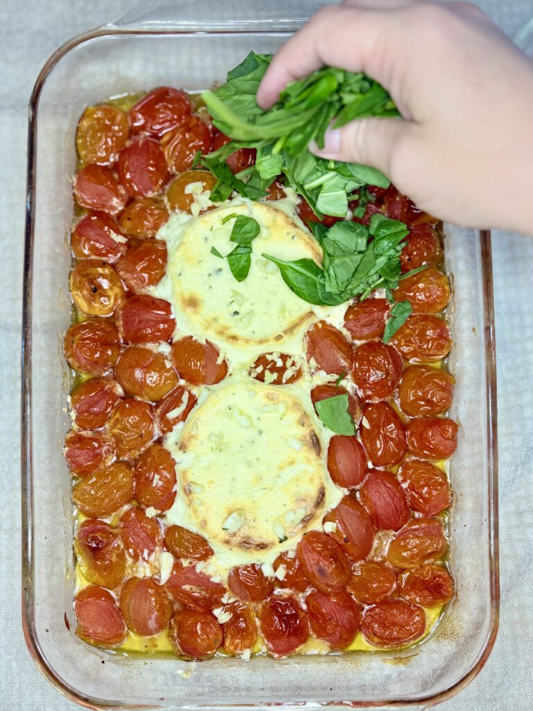 garlic and spinach being added to baked tomatoes and Boursin cheese