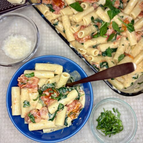 Baked Boursin Pasta in a bowl next to a baking dish on a counter